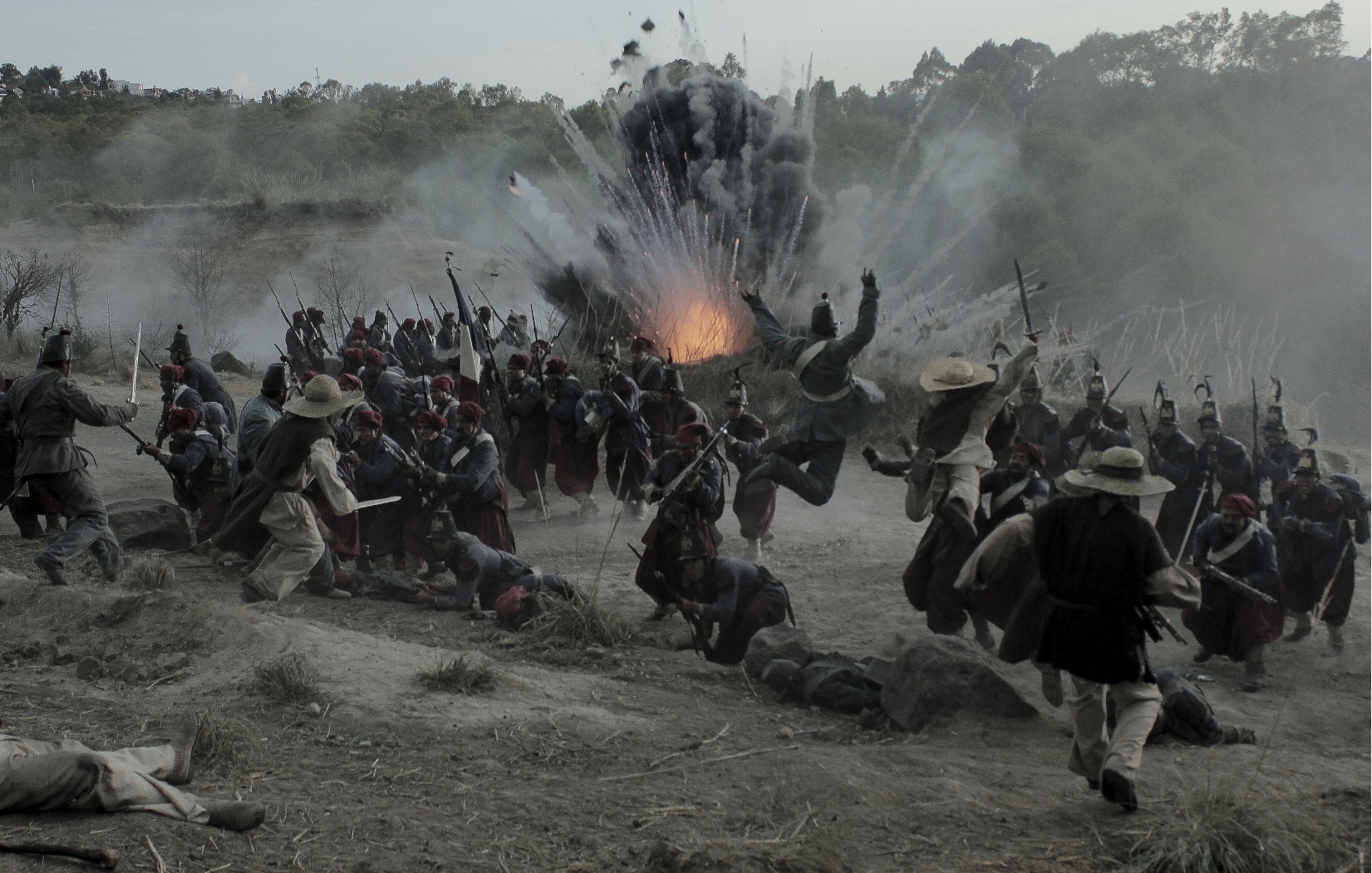 Escena de batalla de época con numerosos participantes y una explosión al fondo